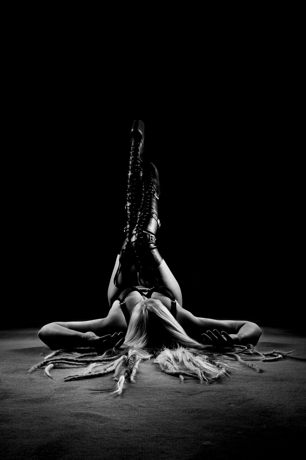 Lady laying down posing in big pole dance boots and lingerie