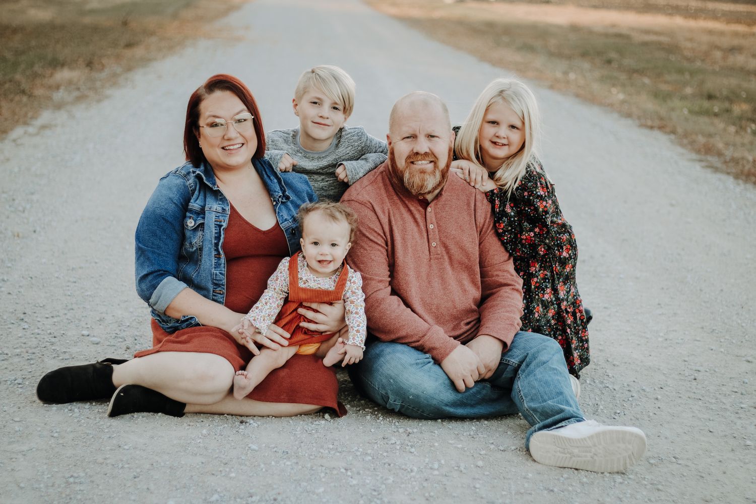 A family relaxes together on a path during a casual outdoor photo session.
