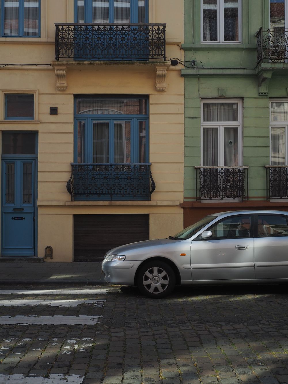 A car parked in front of a yellow and green building