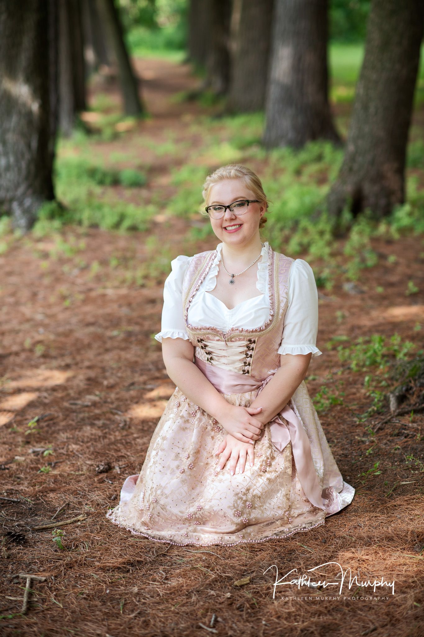 Kathleen Murphy Photography picture of a girl in a dirndl dress in a grove of pines.