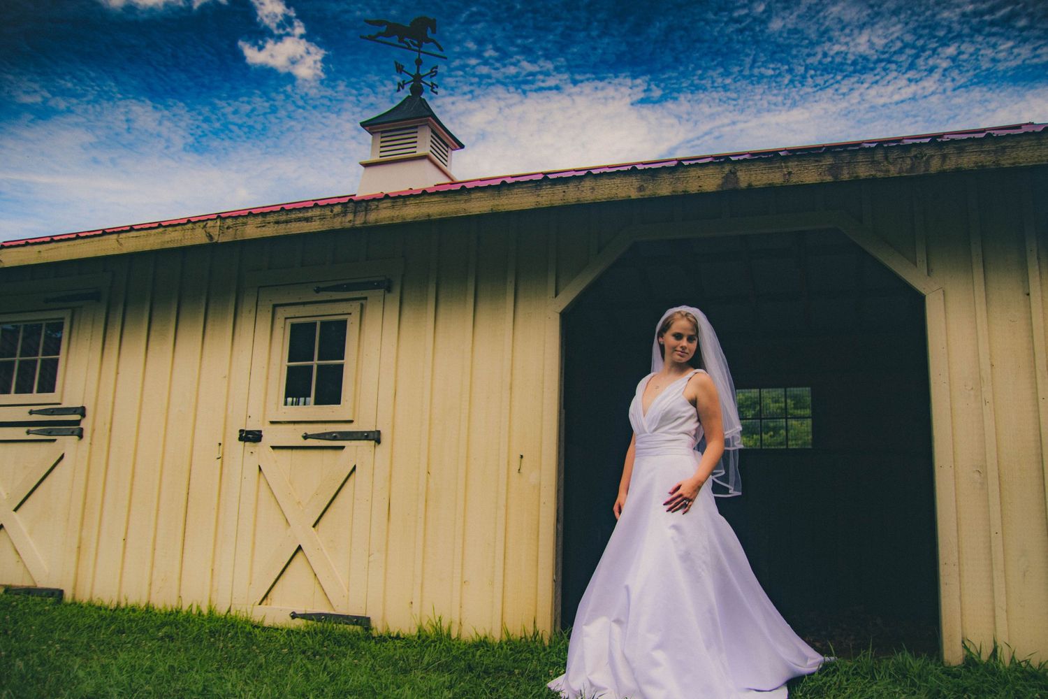 Rustic yellow barn with white trim under bright blue skies.