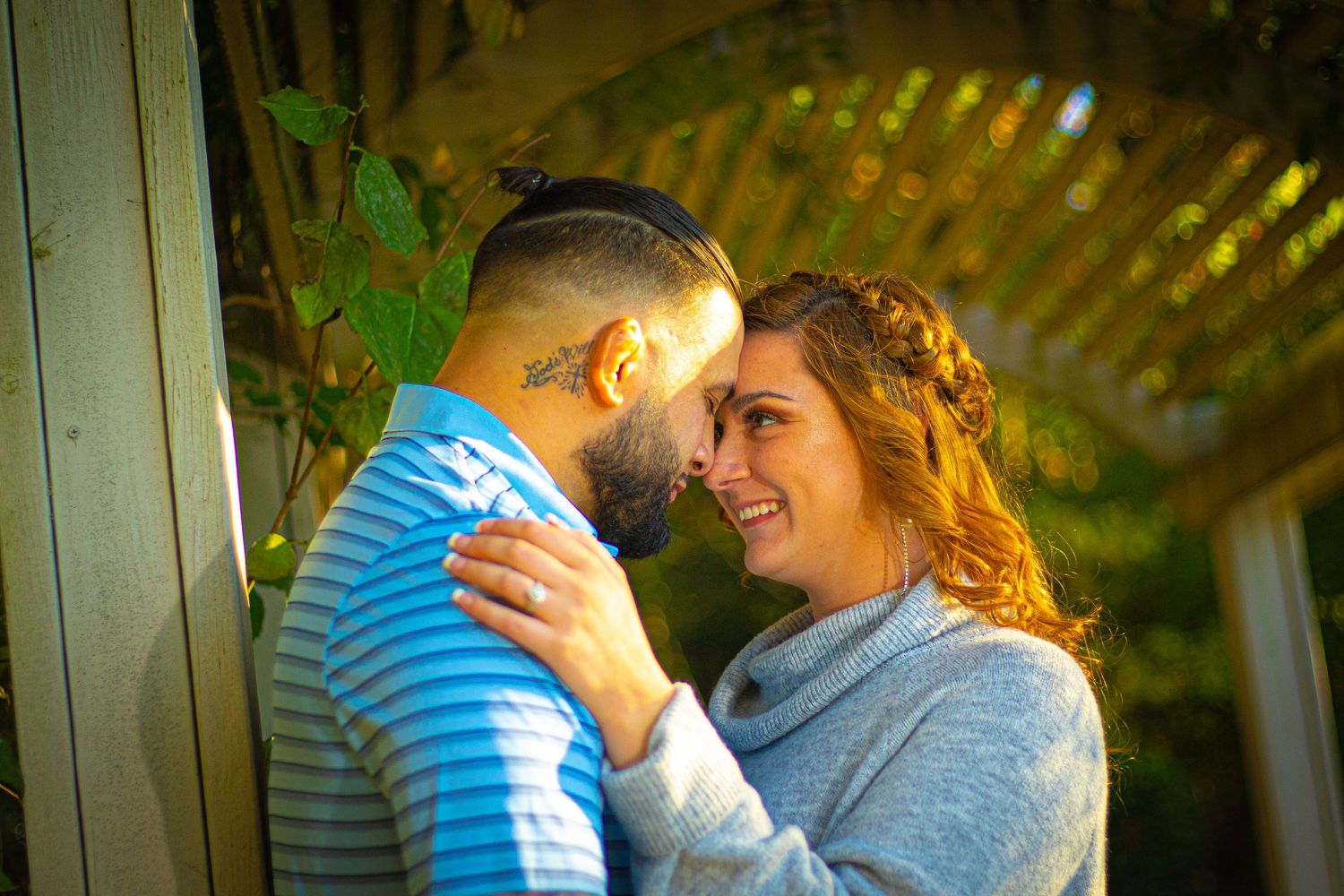 Romantic outdoor photoshoot in golden sunlight under a wooden pergola.
