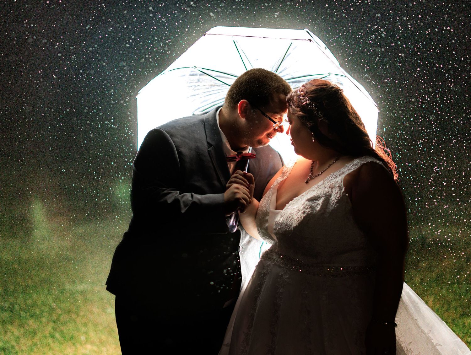 Silhouetted wedding couple portraits with backlit umbrella in rain.