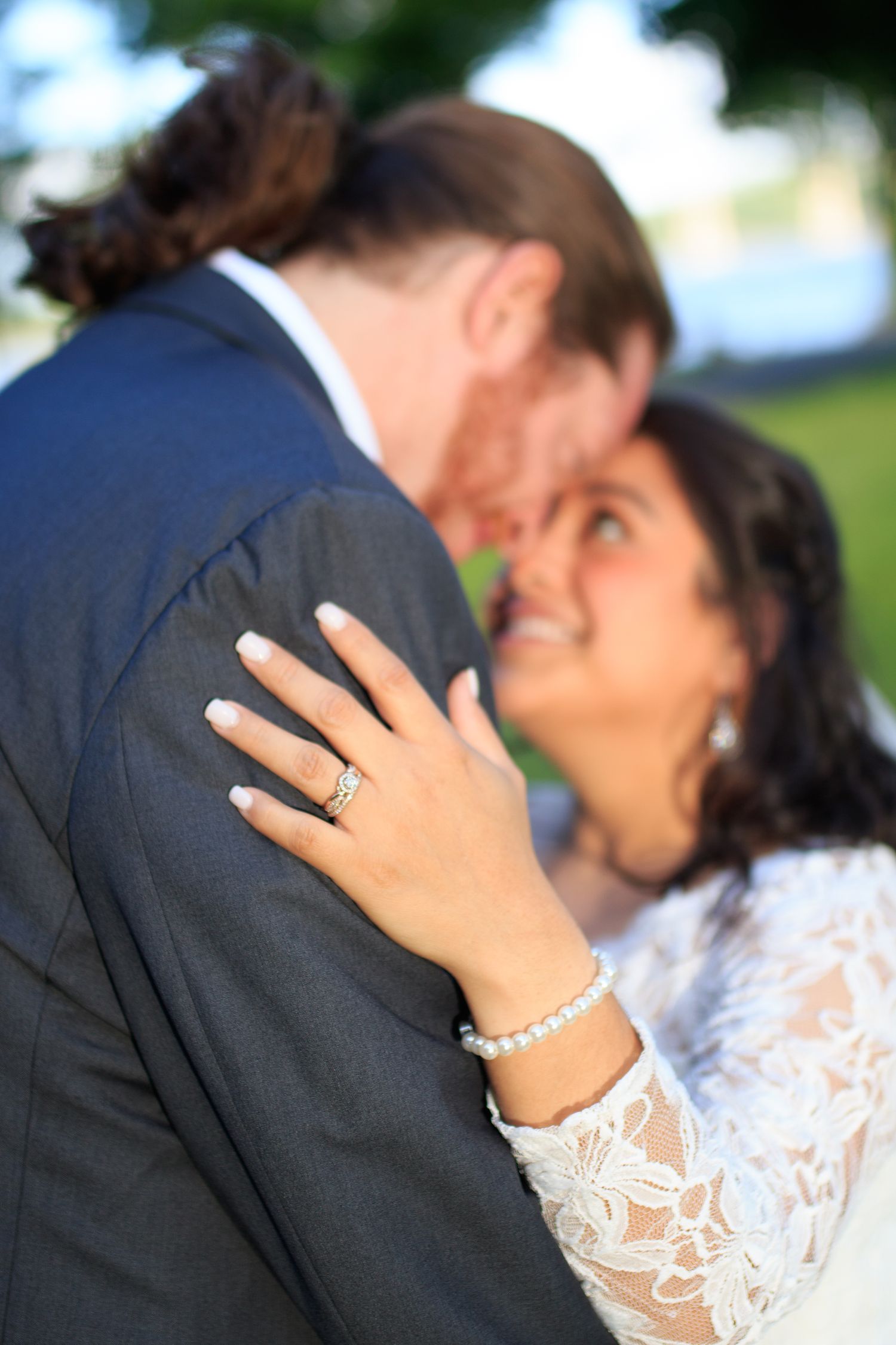 Close-up of couple in wedding attire showing jewelry and lace details.