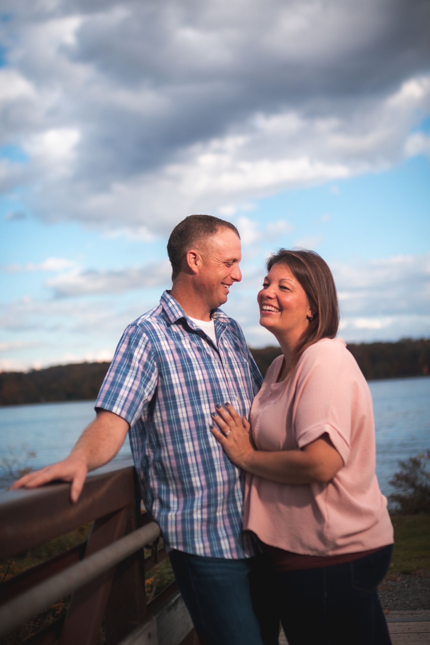 Couple shares a joyful moment together on boardwalk overlooking water.