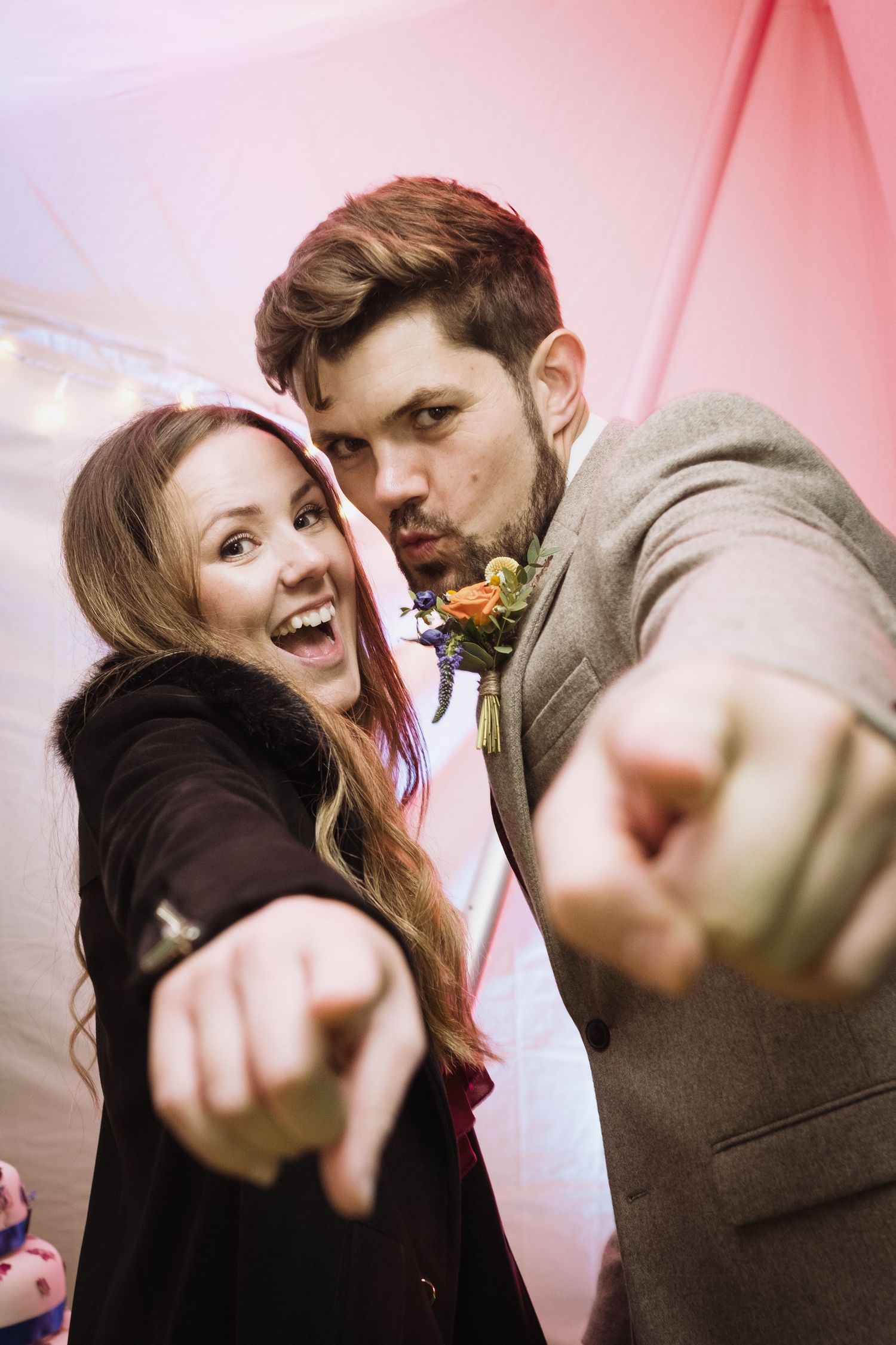 A playful couple points at the camera during their wedding celebration.