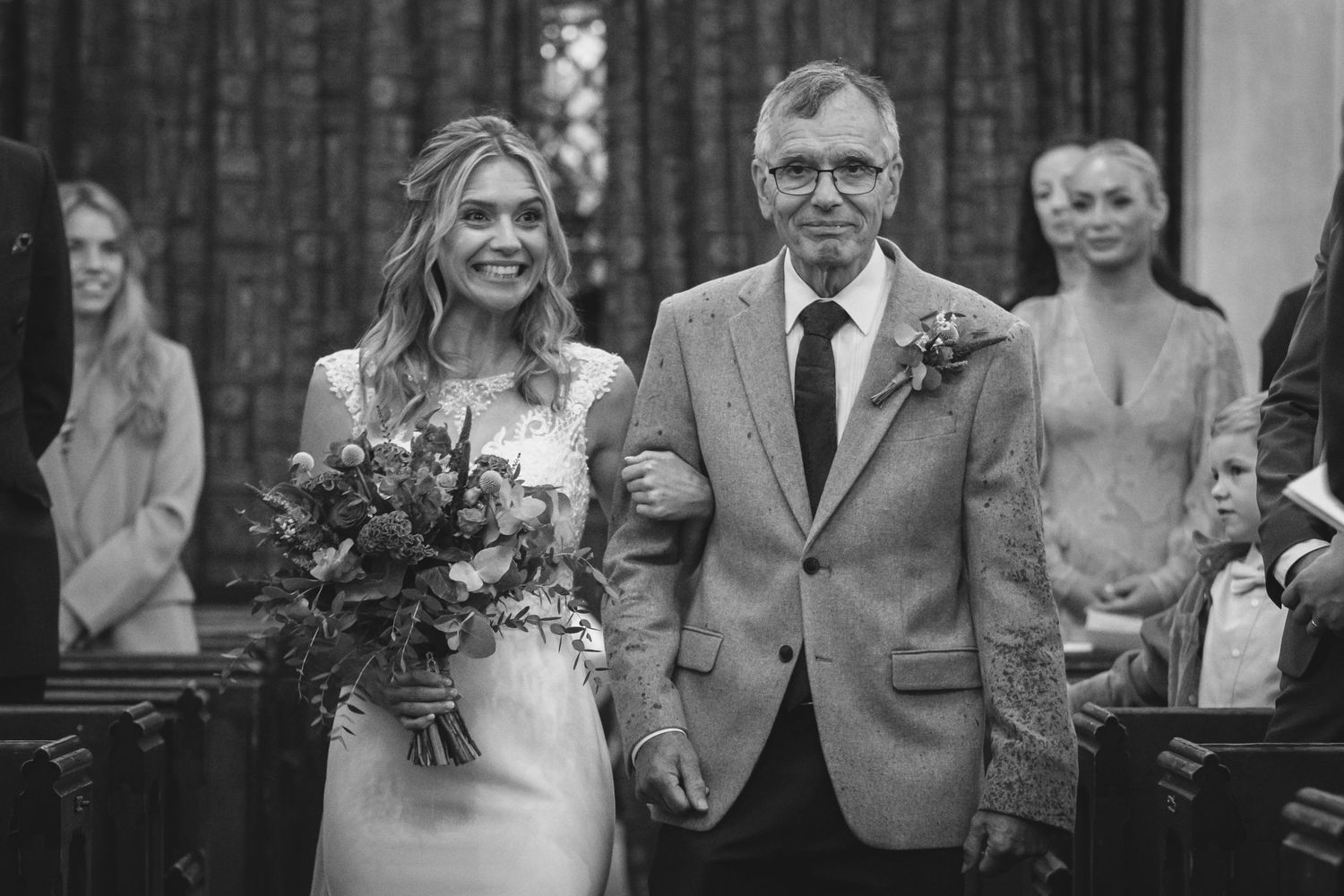 Black and white wedding photo showing a couple walking arm in arm during a church ceremony.