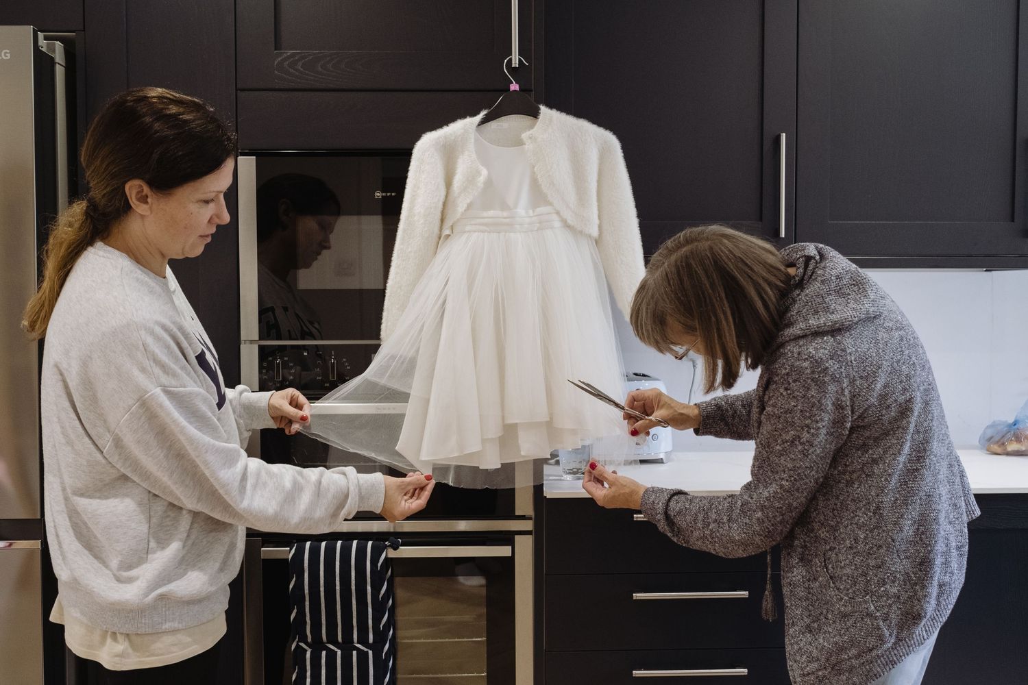 Two women mend a bridesmaid's dress