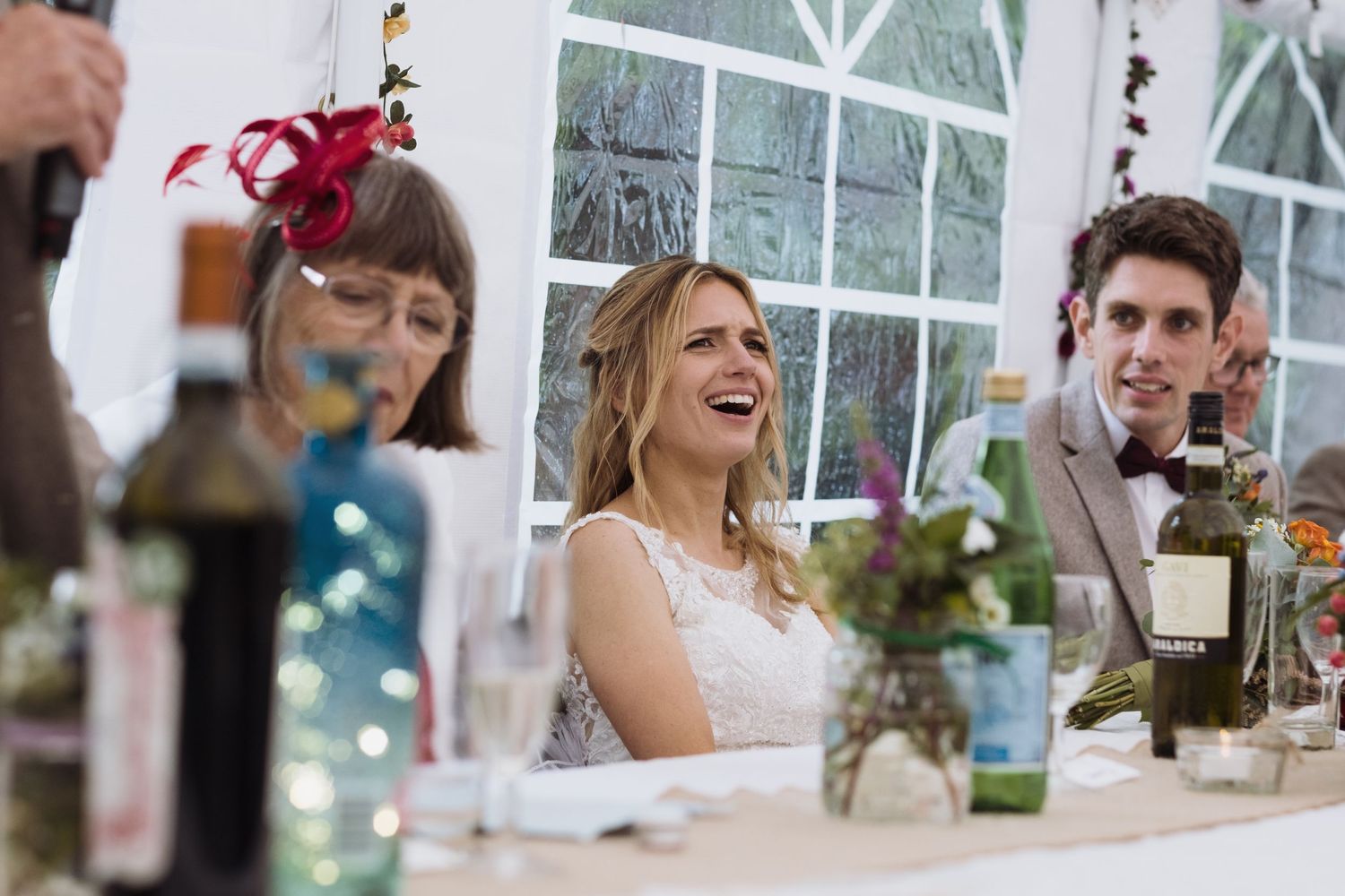 Wedding guests enjoy speeches and celebrations under a decorated marquee.