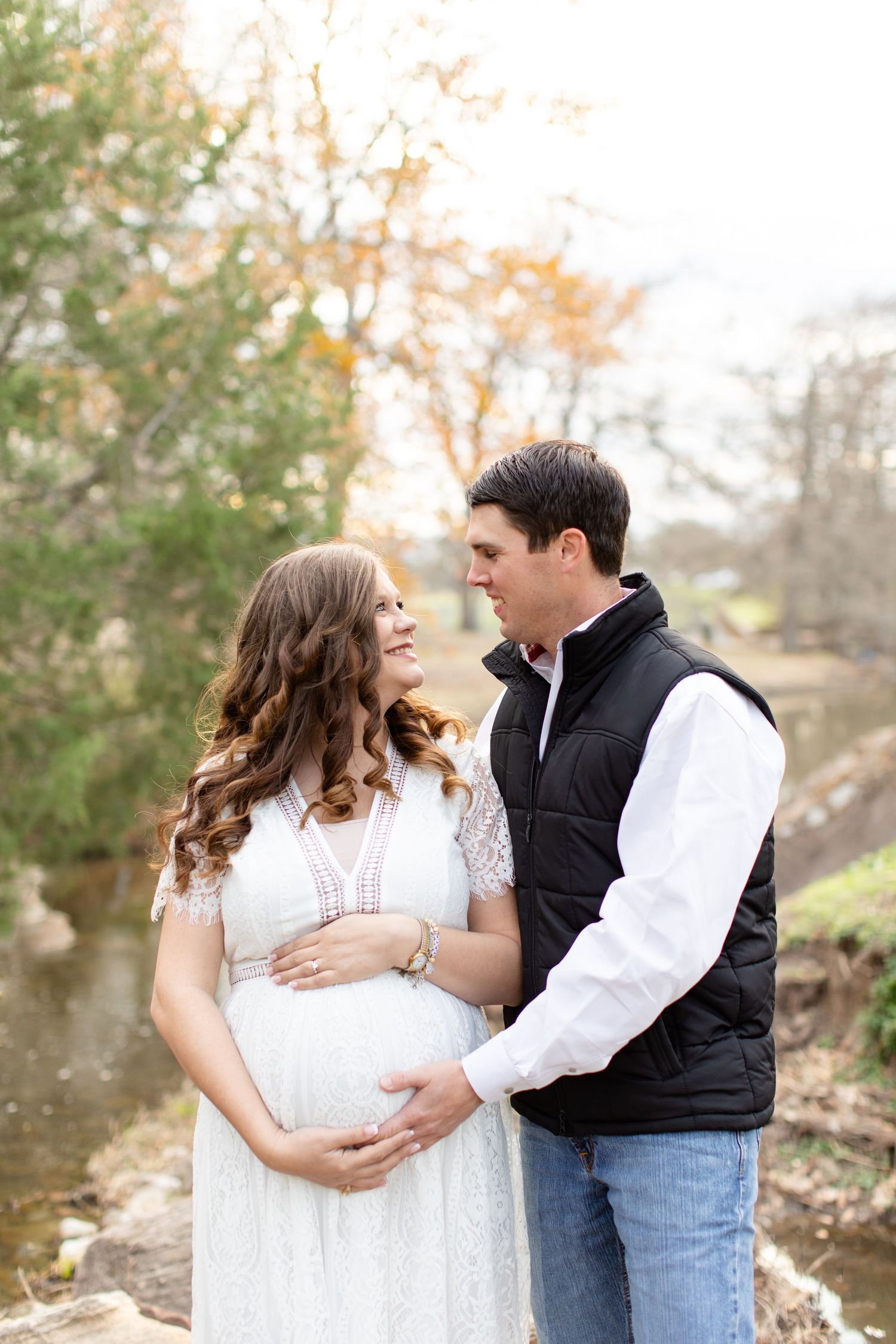 A tender moment between expectant parents by a scenic stream.