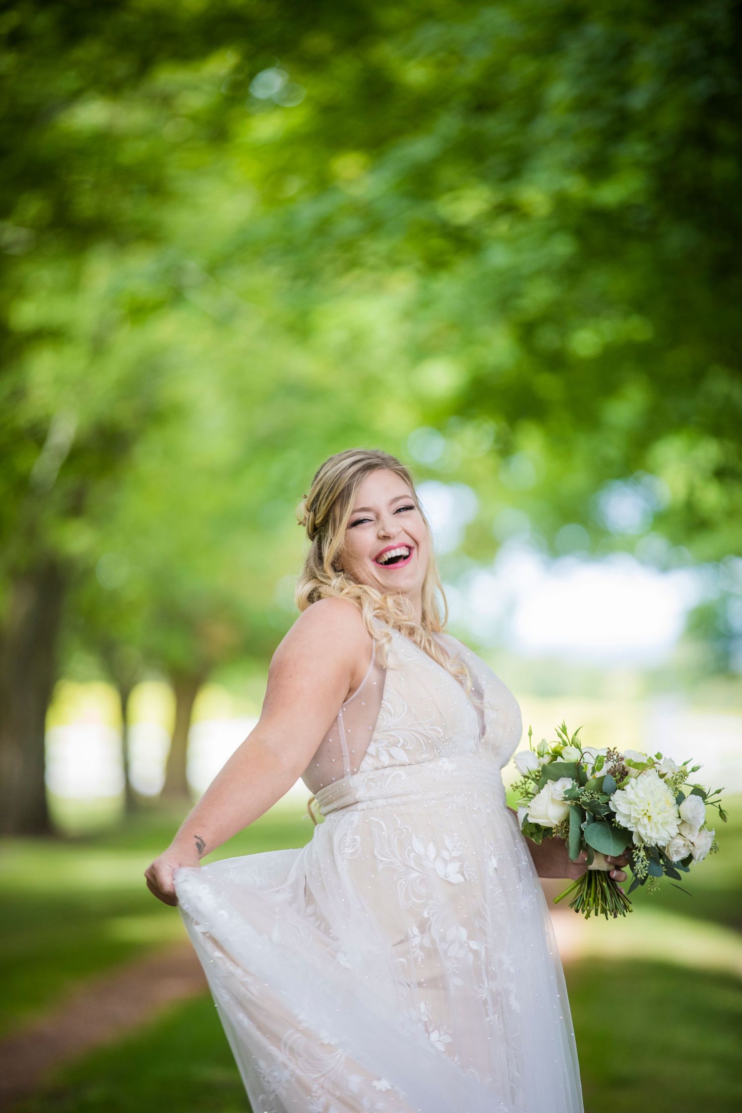Joyful bridal portraits in white dress among green trees and natural lighting.