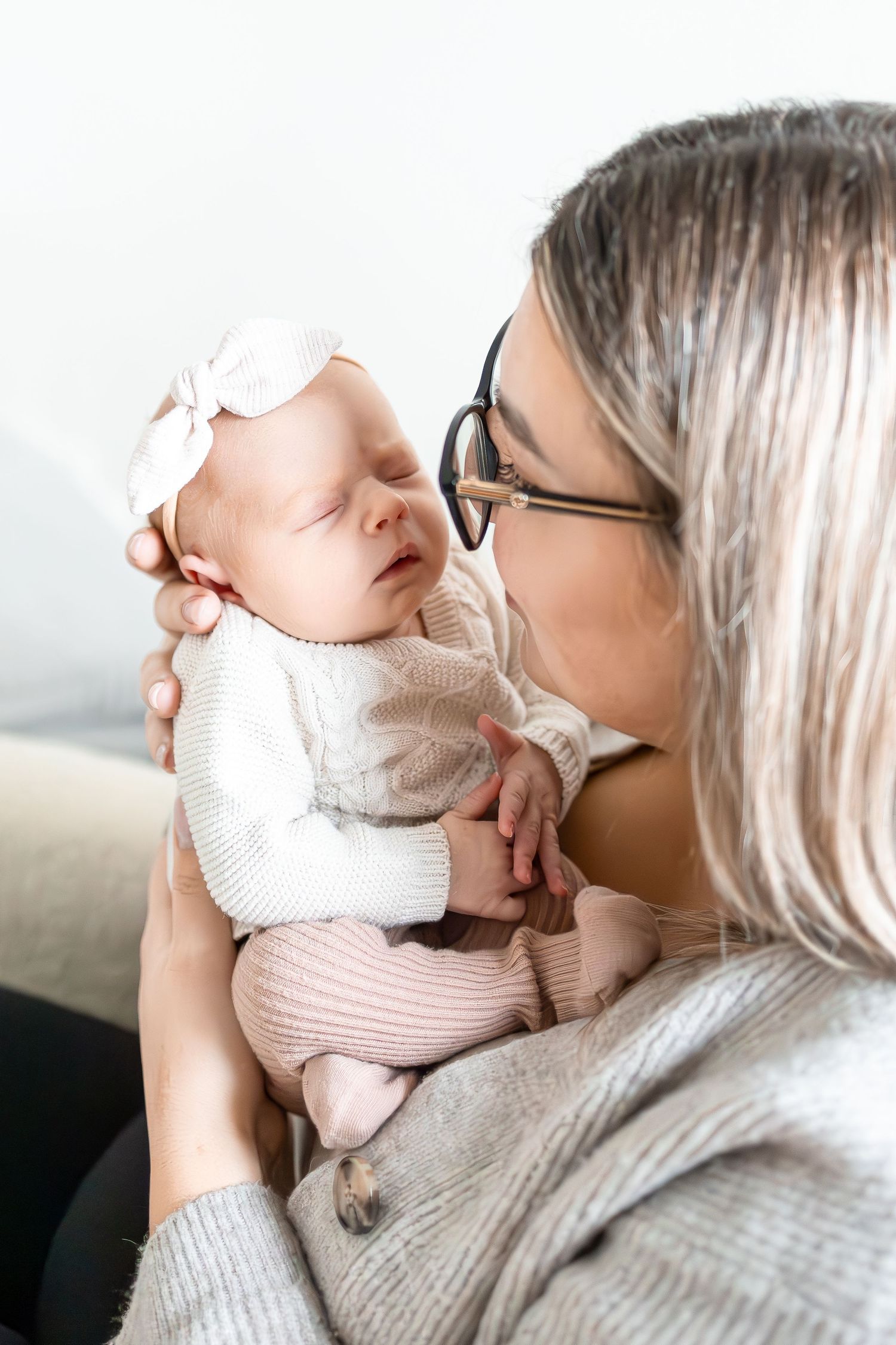 An intimate moment between a caregiver in glasses and their peaceful sleeping newborn.