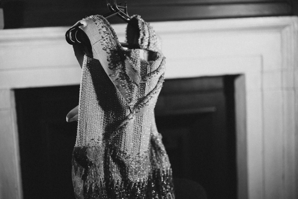 A detailed black and white photograph of an ornate beaded dress on display.
