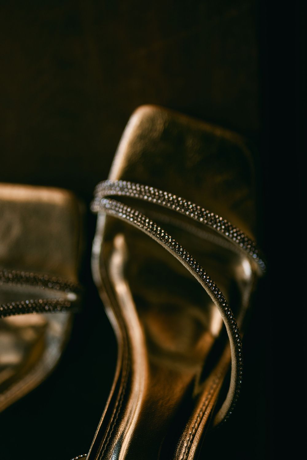 Close-up of a metallic bronze high heel shoe strap with delicate stitching detail.