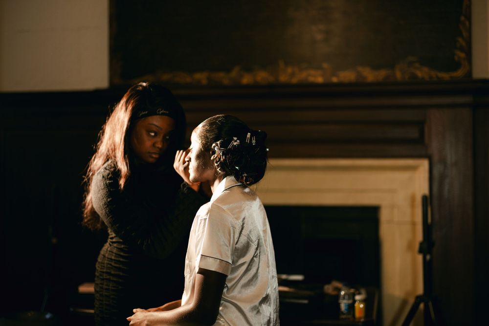 Intimate indoor portrait showing two figures in soft lighting near a fireplace.