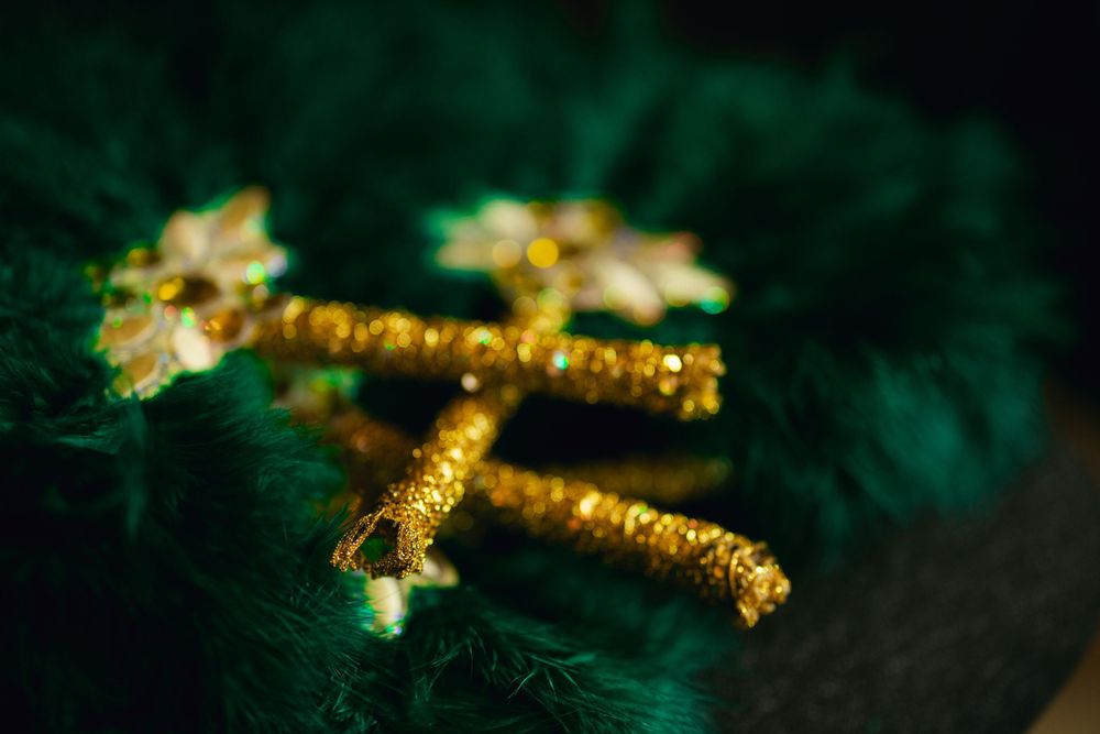 Golden cross pendant with sparkly crystals resting on dark green velvet.