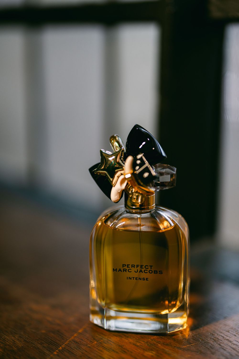 A bottle of Marc Jacobs Perfect perfume sitting on a wooden surface.