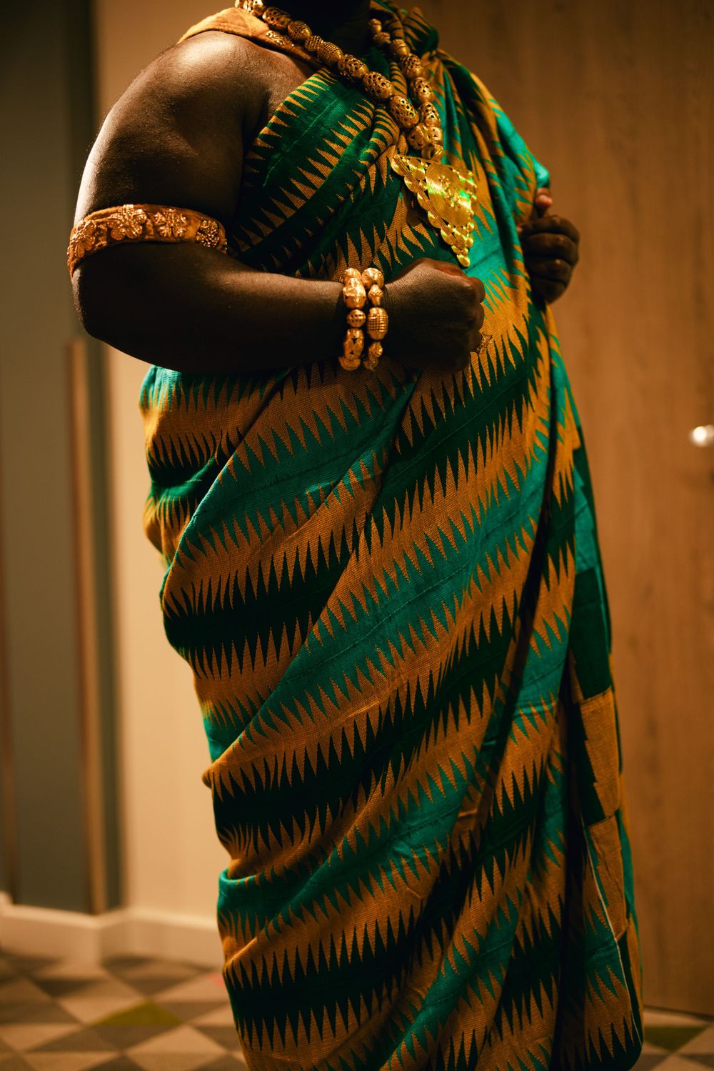 Traditional African attire featuring green and gold striped pattern fabric.