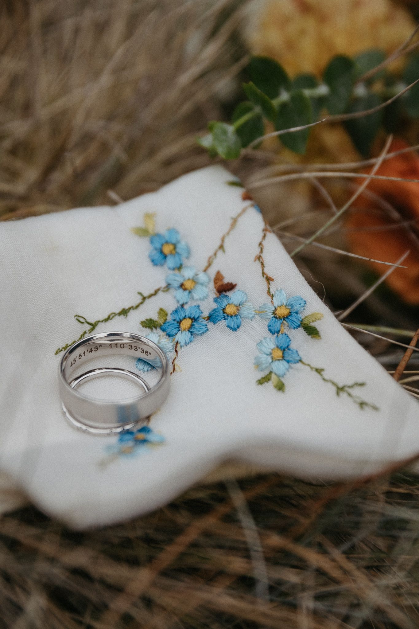 Wedding ring and delicate blue forget-me-not flowers arranged on a white surface.