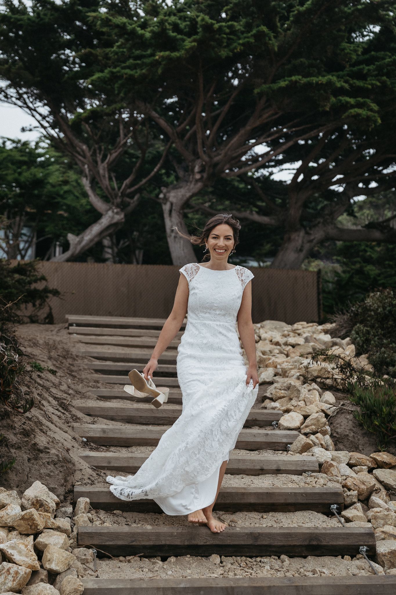 Rustic wooden steps decorated with stones leading upward through coastal vegetation.