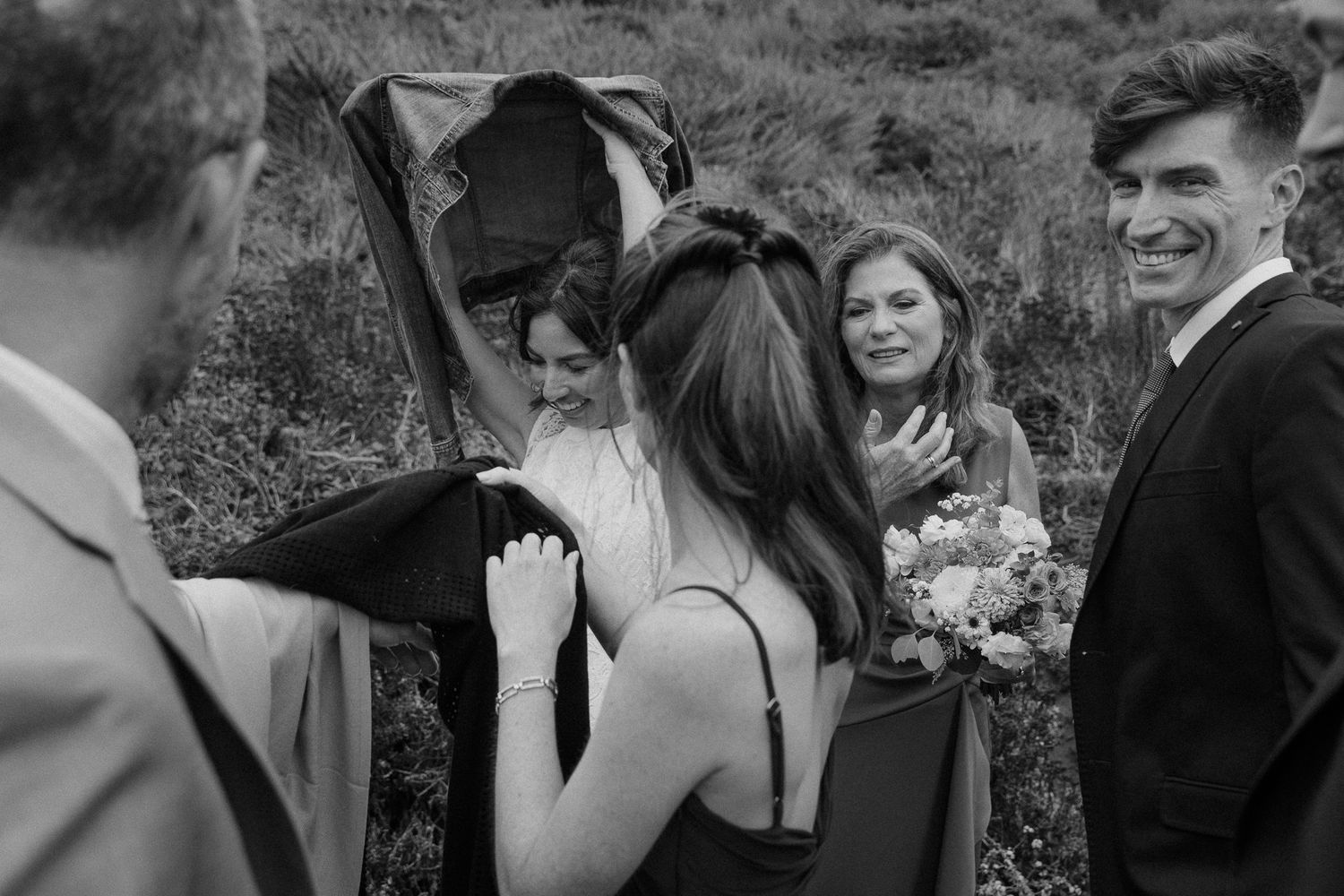 A small group shares laughter and conversation during an outdoor wedding celebration.