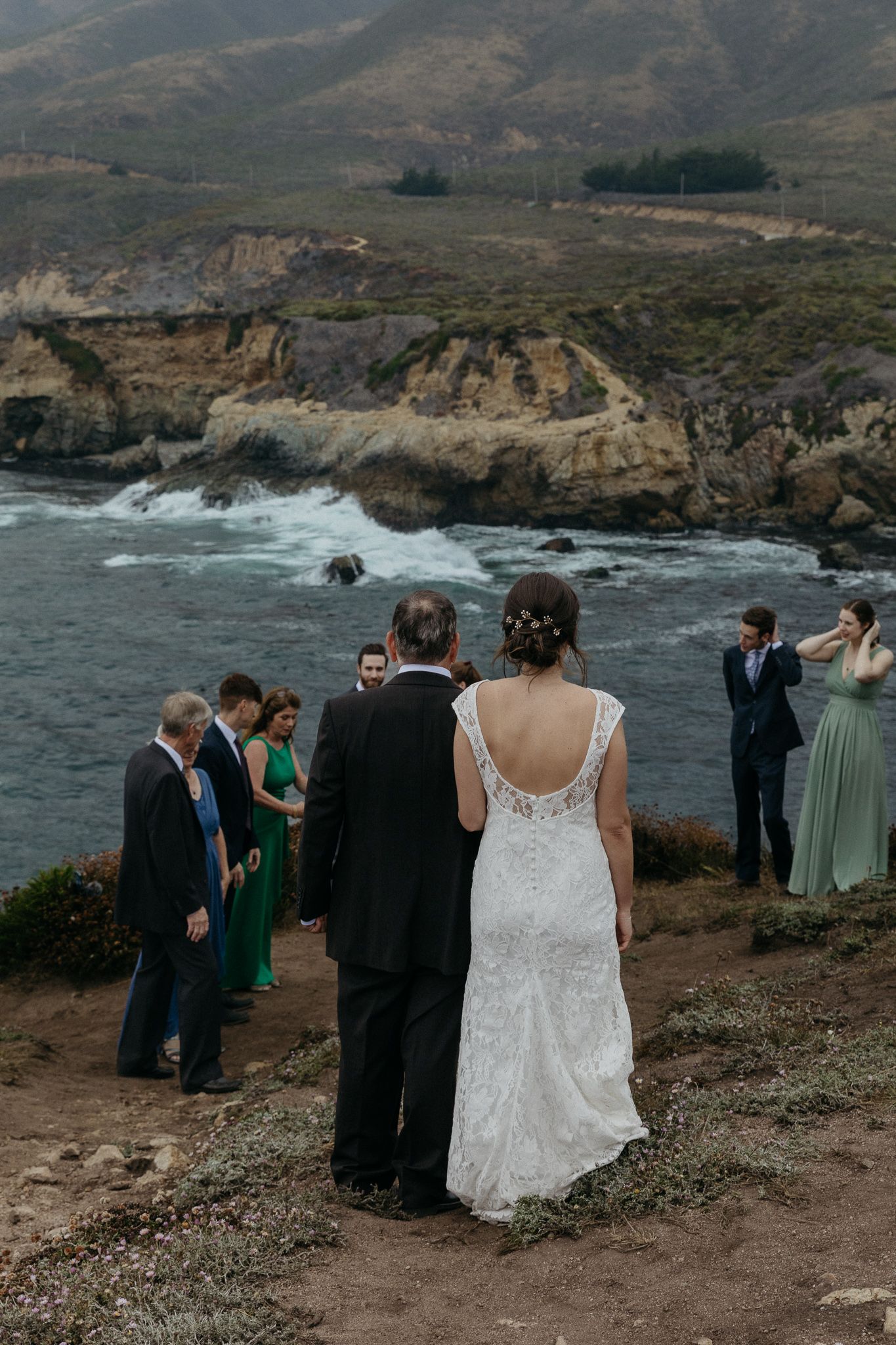 Intimate wedding ceremony overlooking rugged California coastline with dramatic cliffs and crashing waves.