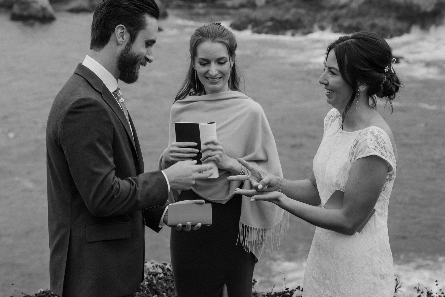 Black and white ceremony moment captured on rugged Pacific coast overlook.