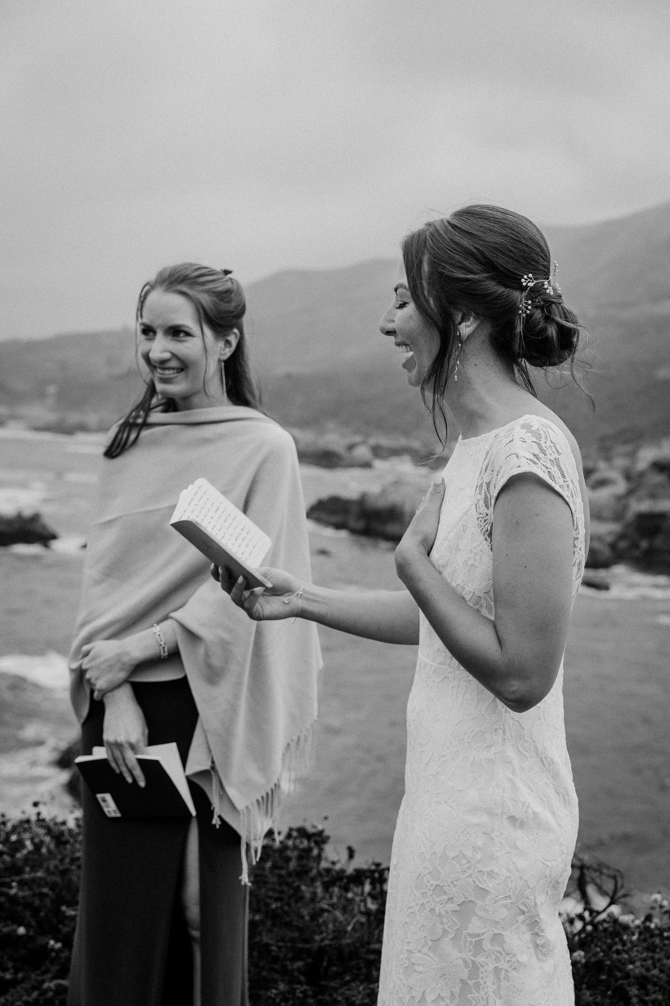 Two figures share a joyful moment during a seaside wedding ceremony.