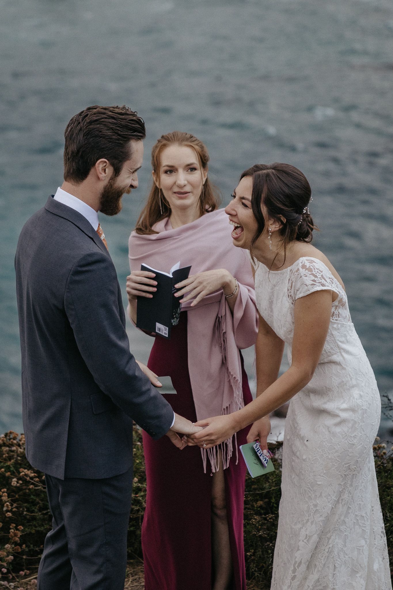 An emotional moment during a cliffside wedding ceremony overlooking the ocean.