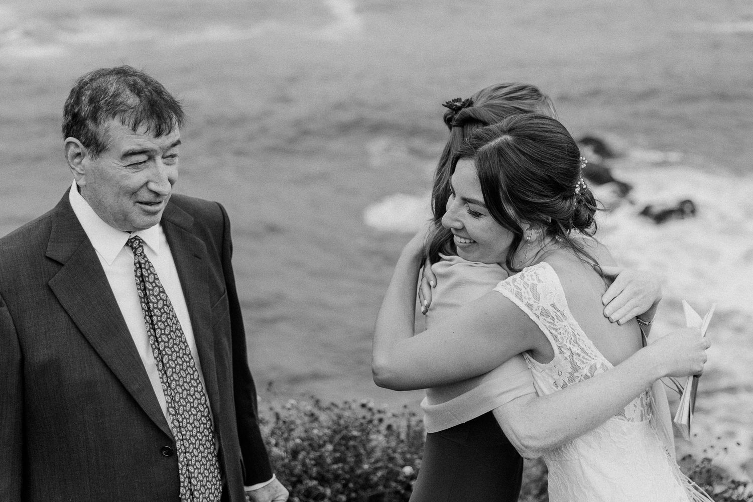Emotional wedding moment captured in black and white by the coastline.