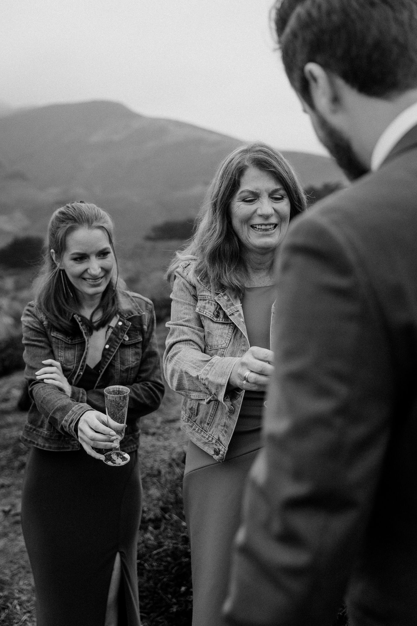 Wedding celebration with guests sharing drinks on coastal cliffside.