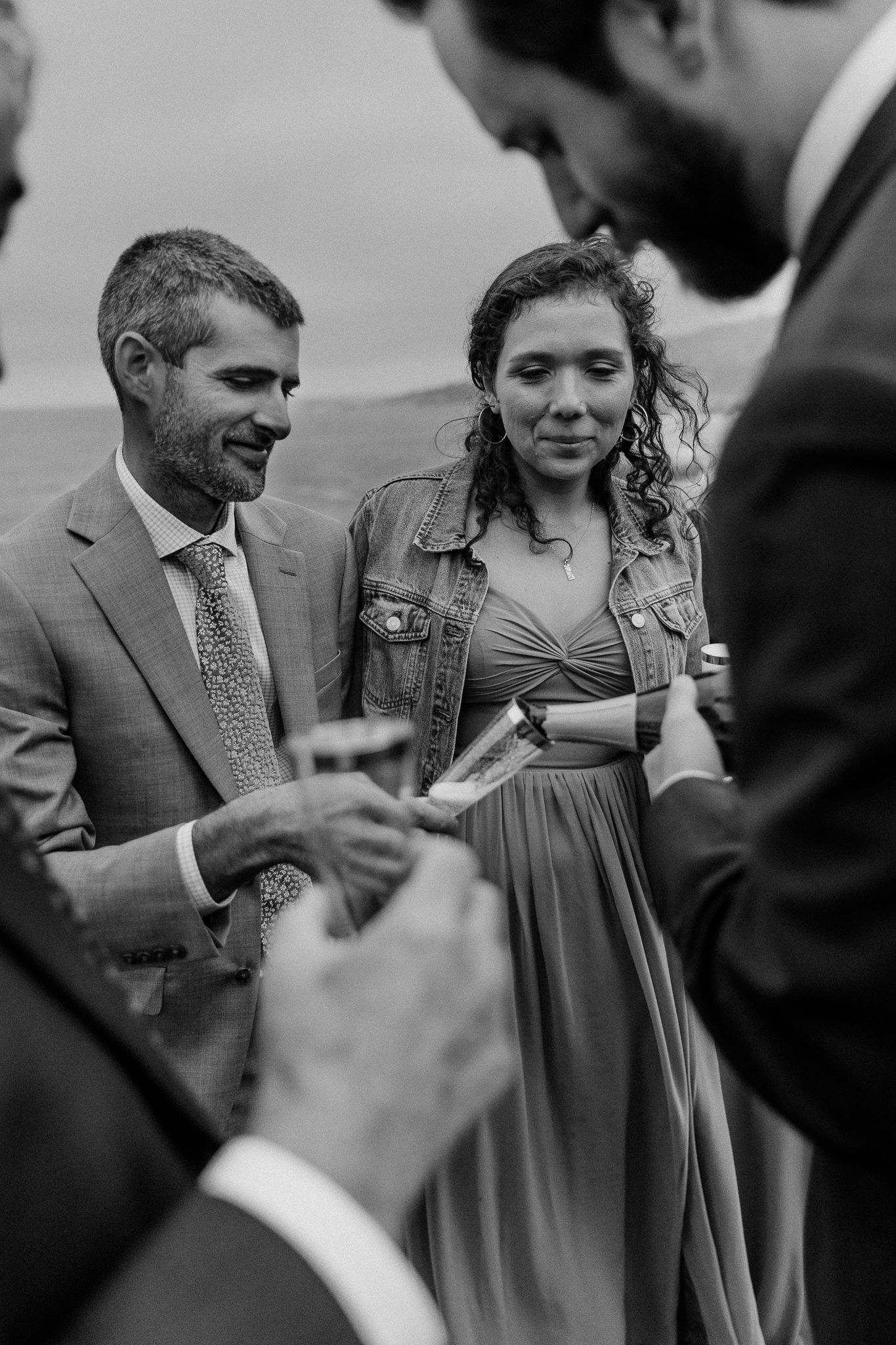 Wedding guests engaging in conversation while holding drinks outdoors.