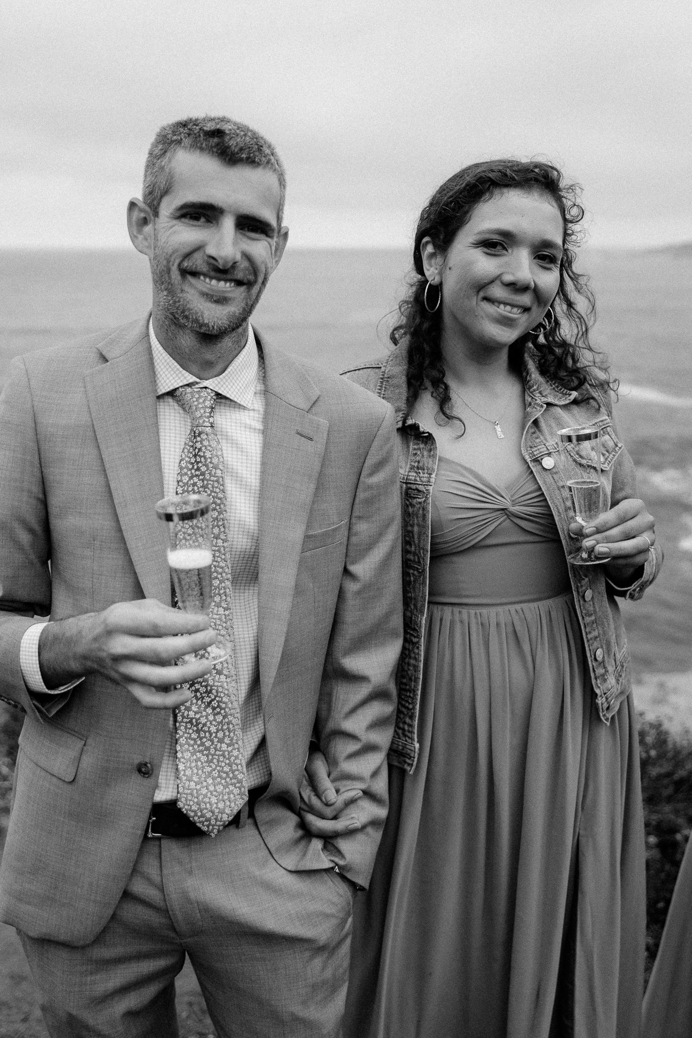 A couple shares a celebratory moment with drinks at their outdoor wedding reception.