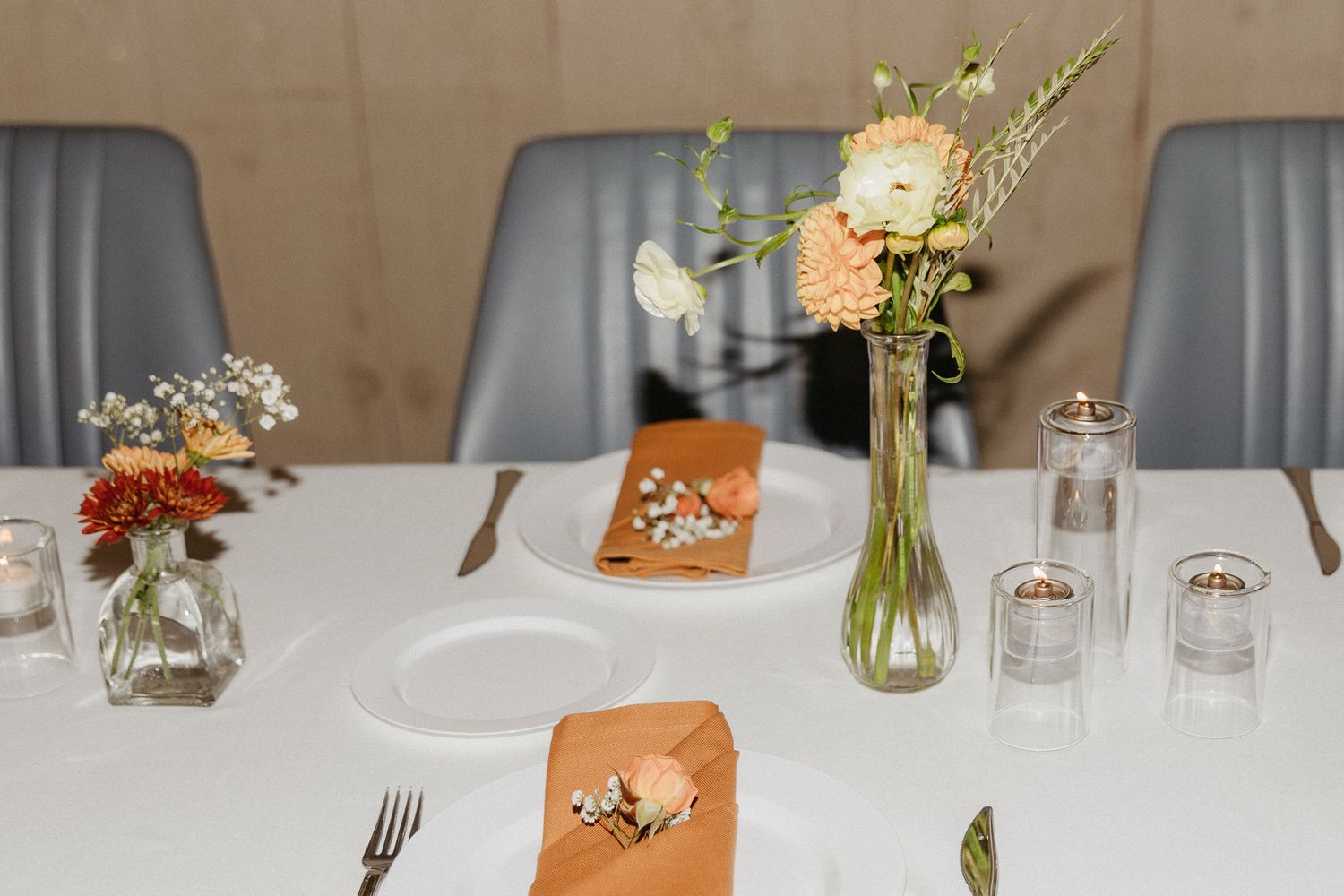 Elegant wedding table setting with small floral arrangements in glass vases.