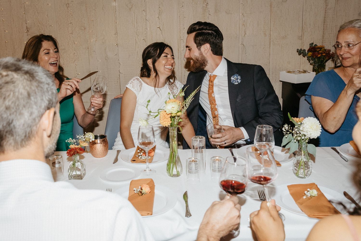 Wedding guests toast and celebrate around an elegant dinner table with wine and candles.