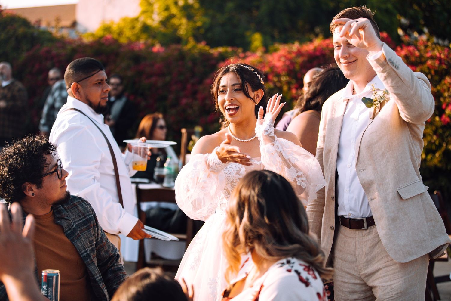 Wedding guests celebrate with the couple during an outdoor reception.