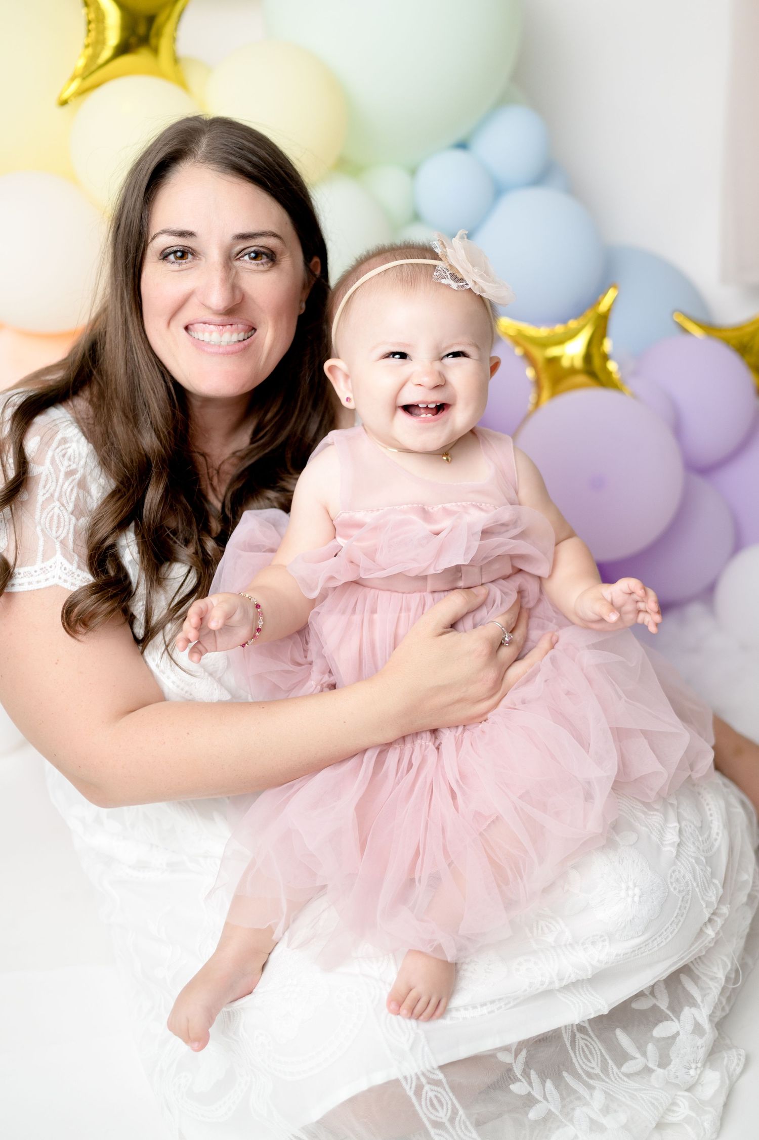 Sweet milestone portrait with pastel balloons and gold stars in backdrop.