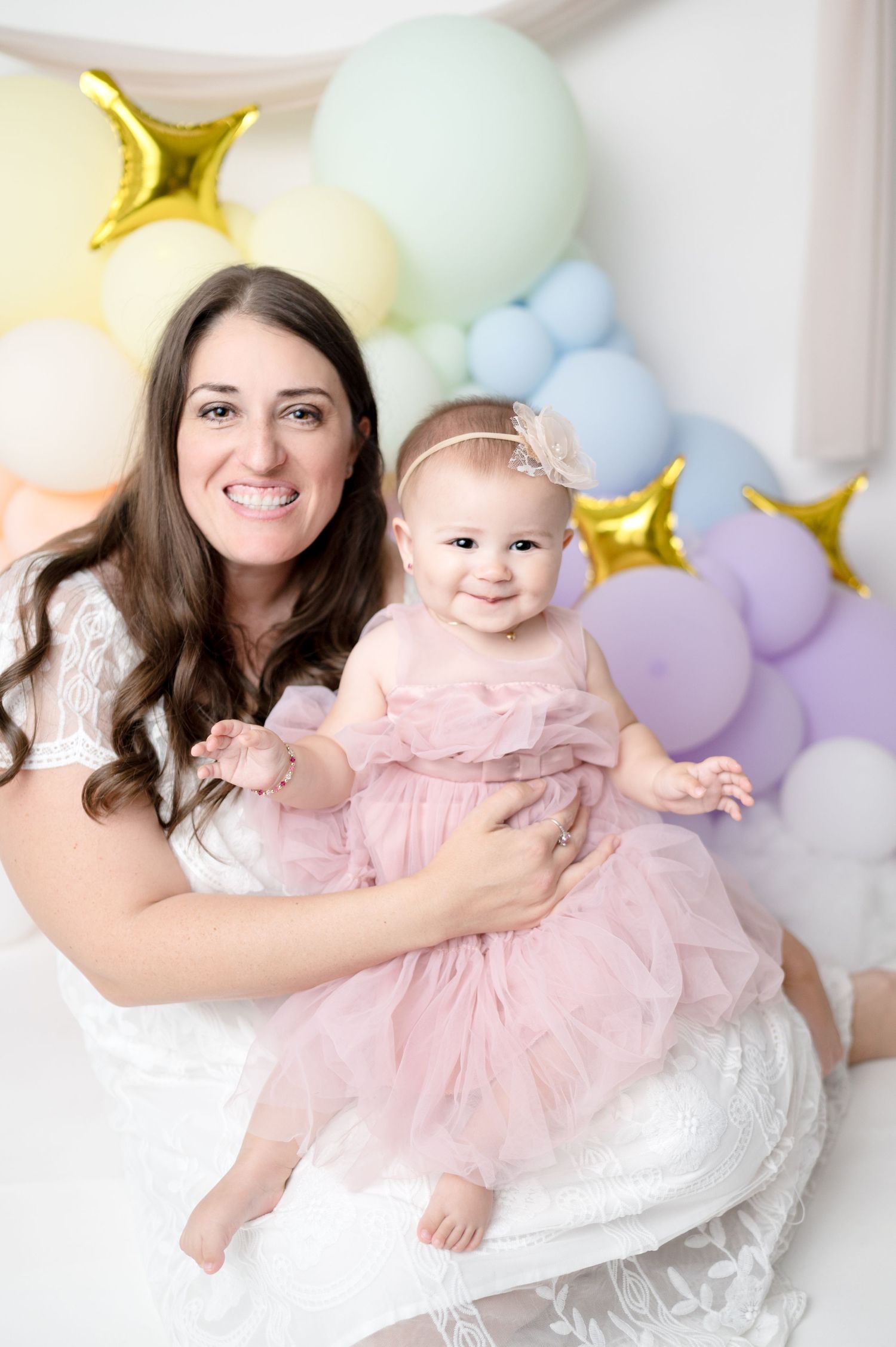 Sweet celebration portrait with pastel balloons and gold stars in background.