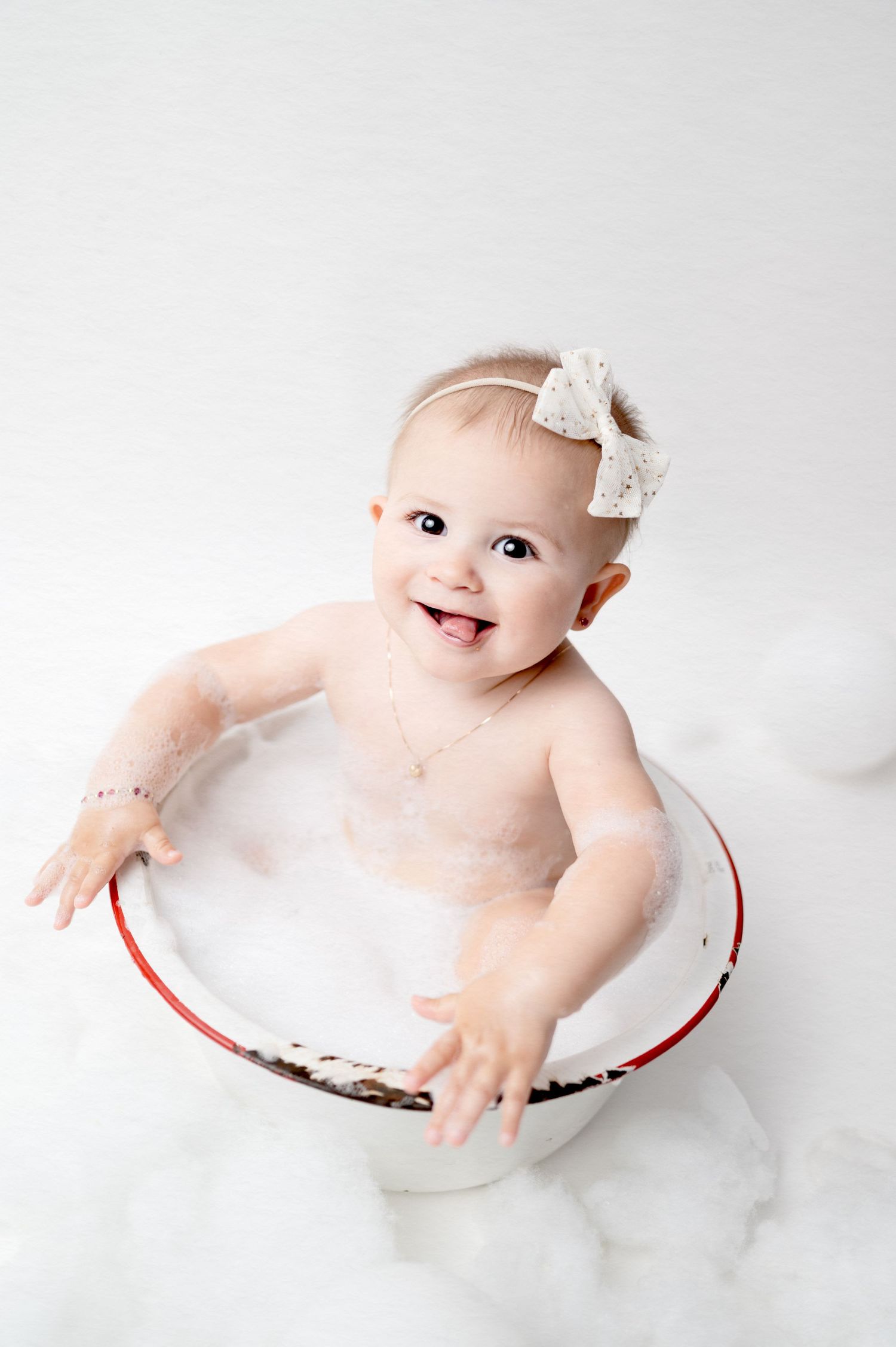 Sweet baby sits in vintage enamel bowl smiling during milestone photo session.