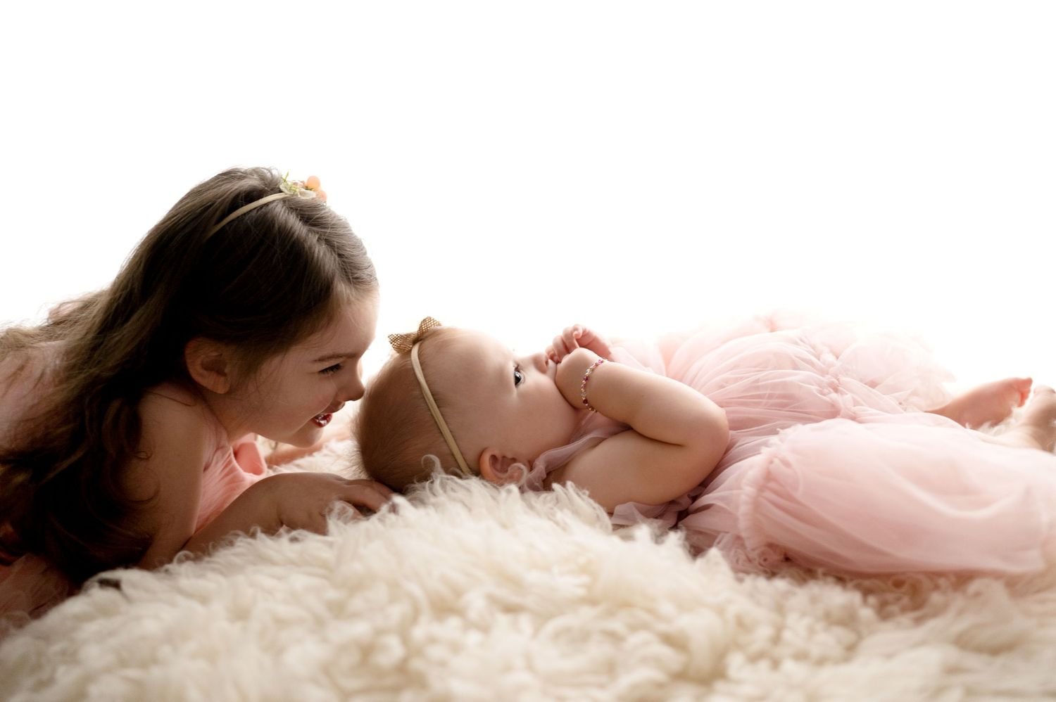 Intimate lifestyle portrait on fluffy white rug with soft side lighting.