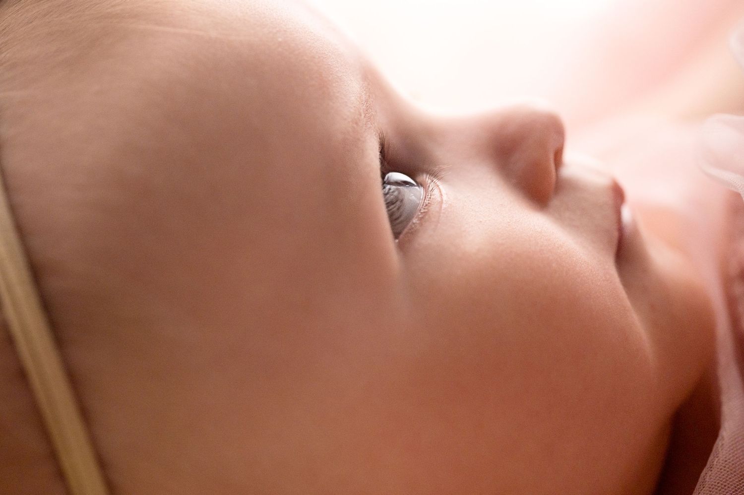 Close up artistic photo of baby's eye and soft features in gentle lighting.