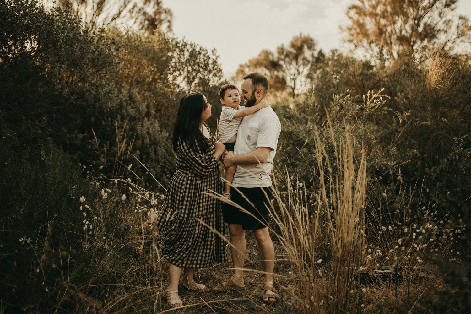 A family shares an intimate moment together in a rustic outdoor setting at golden hour.