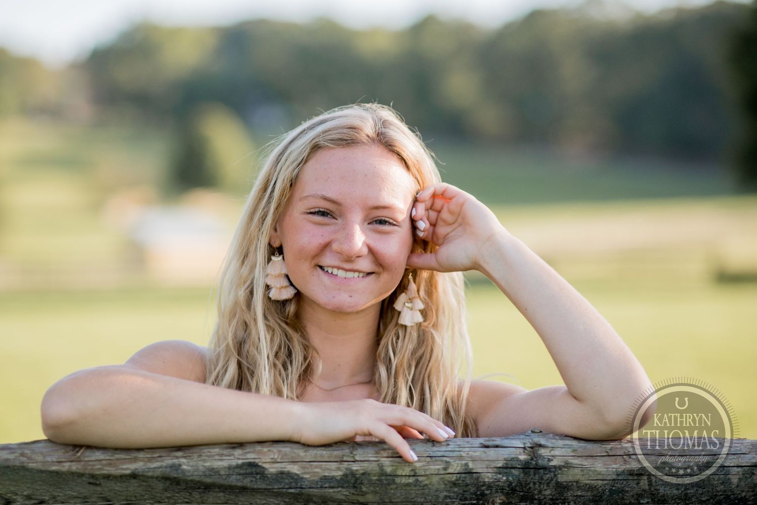 Outdoor portrait leaning on weathered wooden fence in afternoon sunlight.