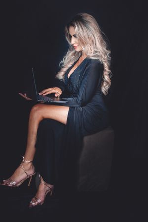 Dramatic low-key photos with laptop and evening wear against black background.