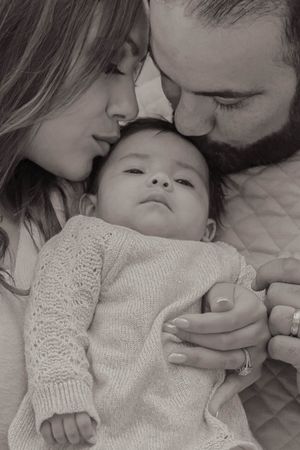 Black and white intimate portrait of family bonding with baby in knit sweater.