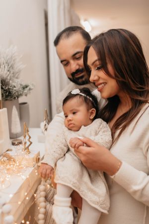 Candid family moment by holiday decorations and twinkling lights in warm neutral tones.