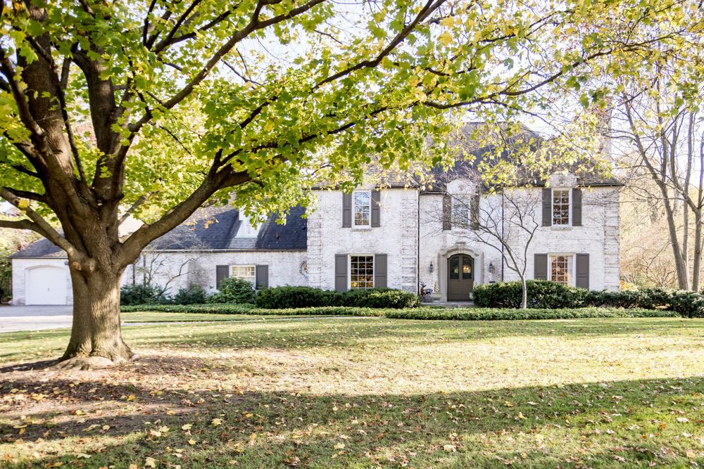 Stately property surrounded by mature trees showcases traditional colonial architecture.