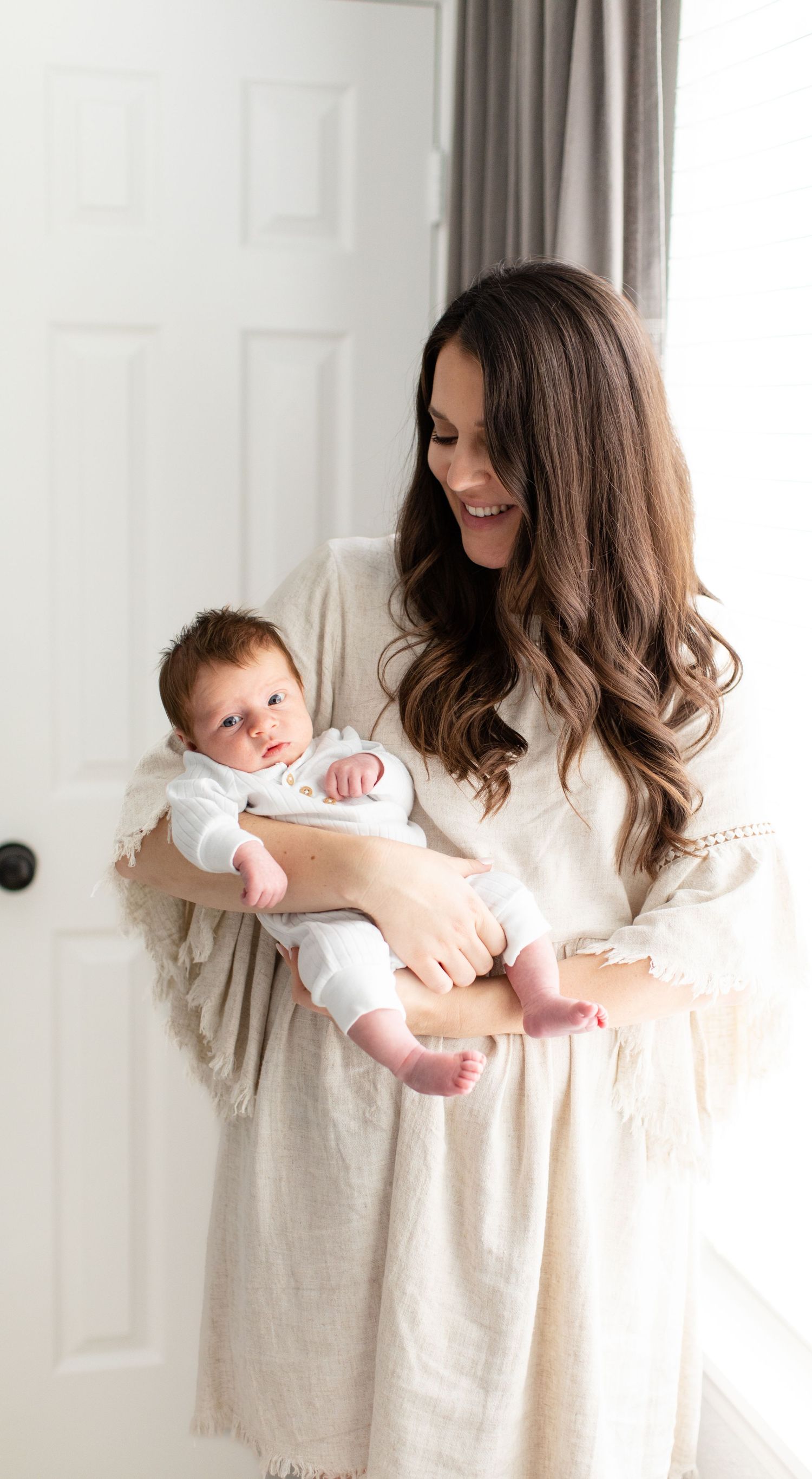 A tender moment between parent and infant captured in a bright, minimalist nursery setting.