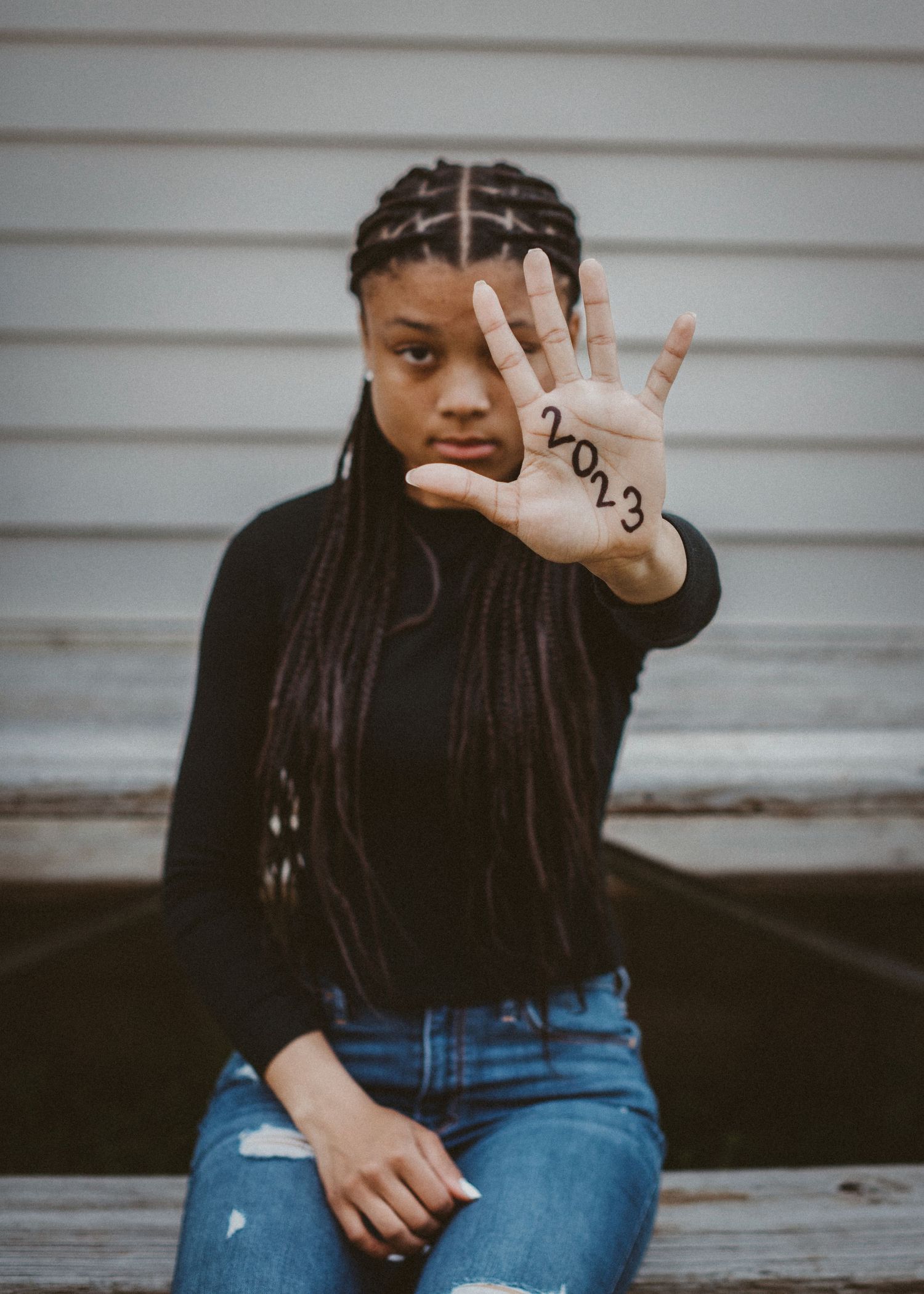 Senior session girl holding hand up with 2023 written on palm. Captured by Maryland Photographer Mallory Bramlett.