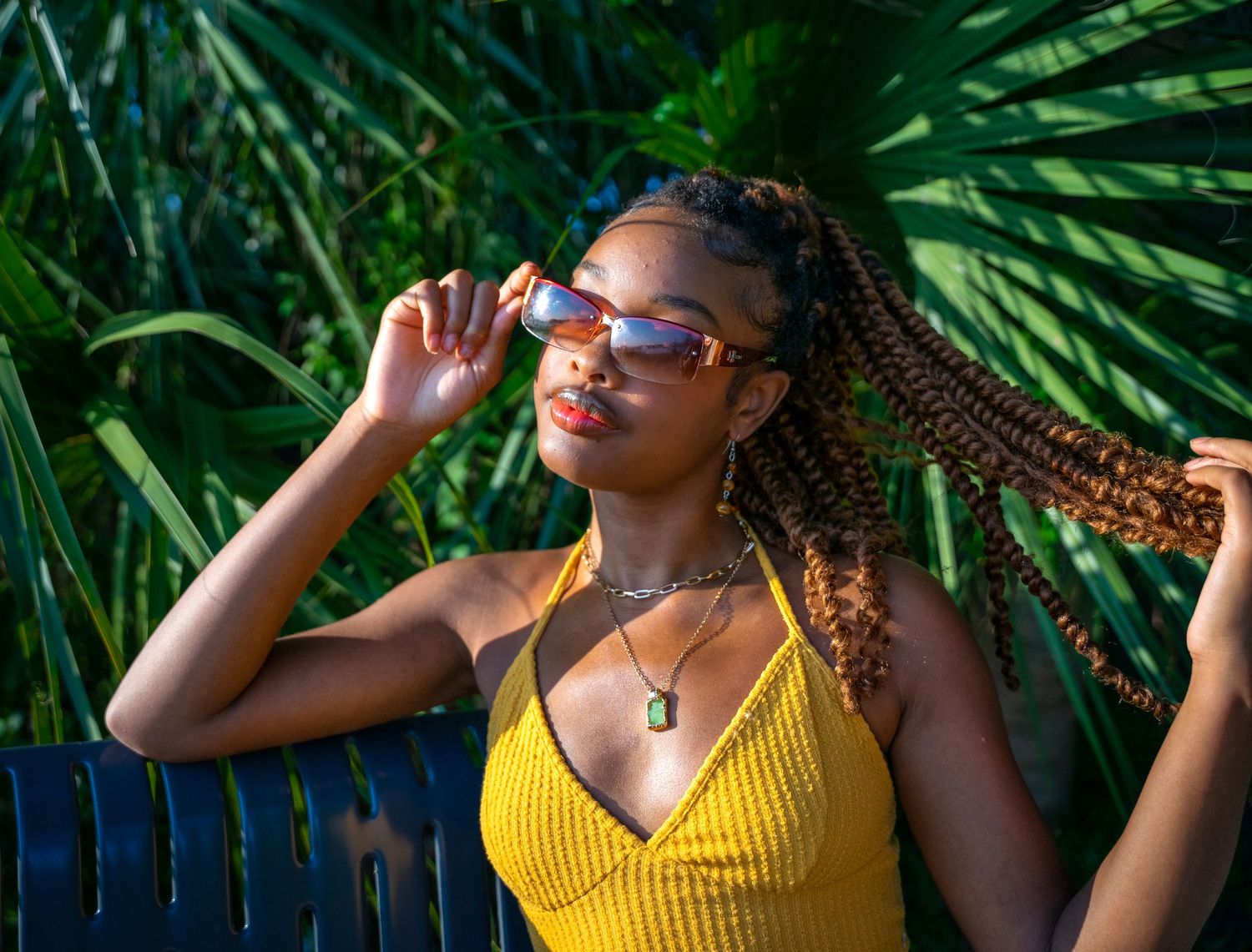 Summer fashion photoshoot featuring yellow top against tropical palm background.